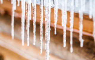 Long Icicles Melting of a Log Wood Chalet roof top