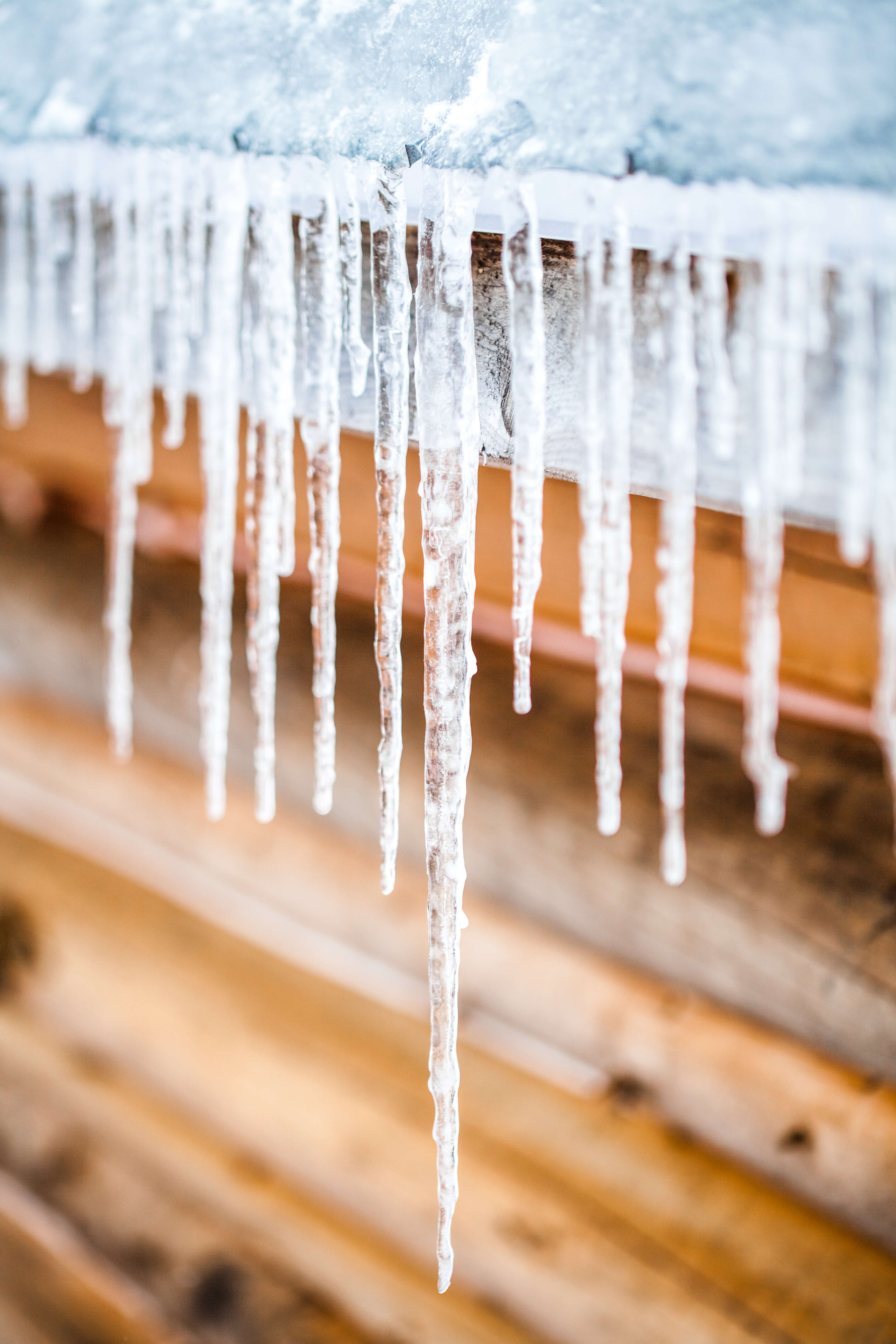 Long Icicles Melting of a Log Wood Chalet roof top